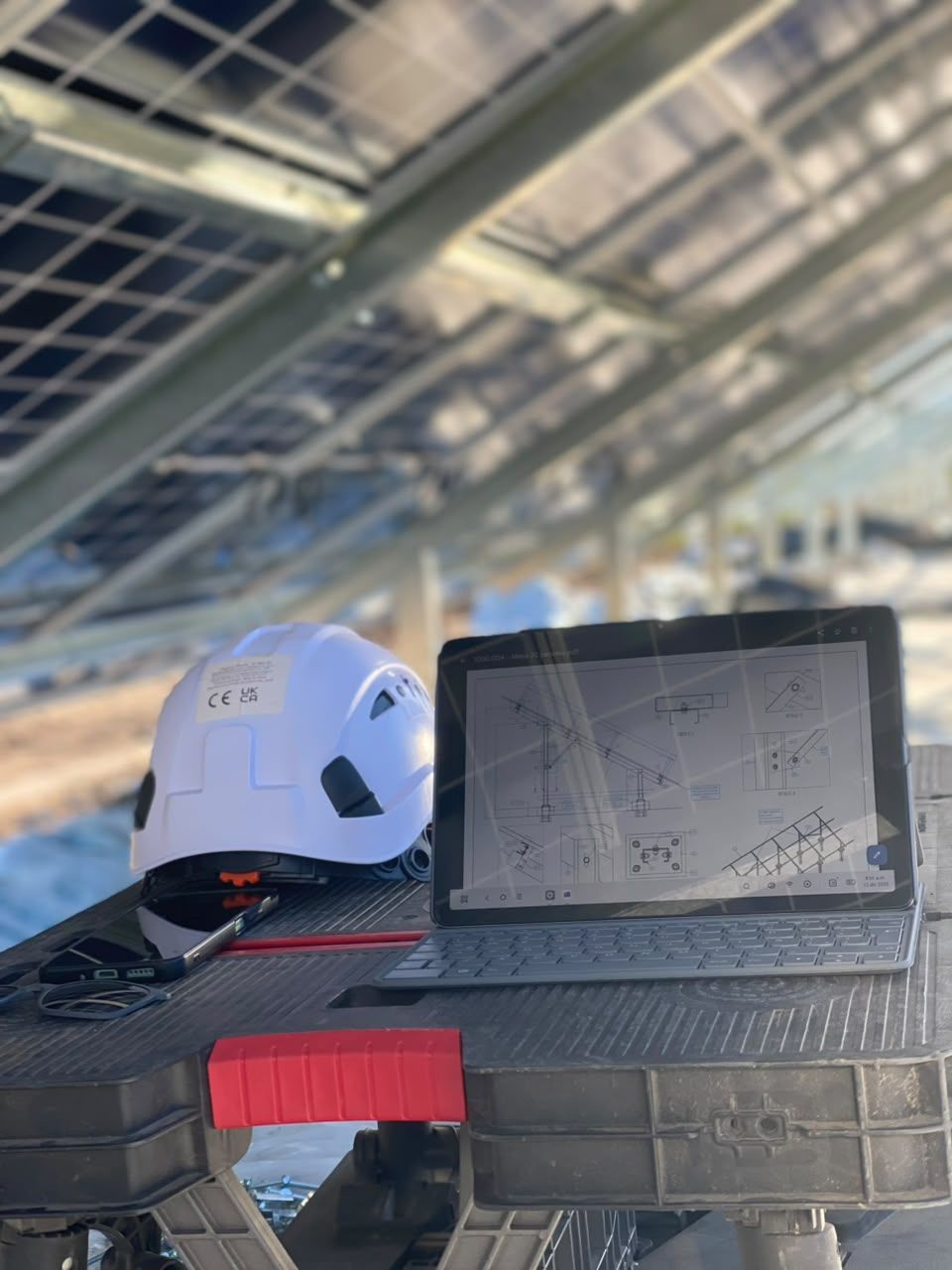 Casco y tablet con planos de estructura solar en obra