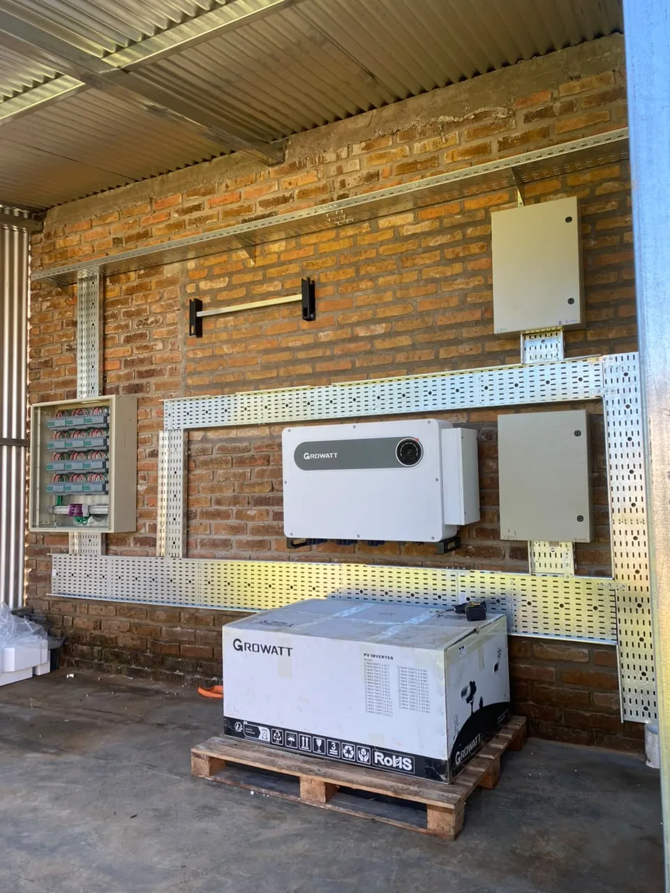 Sala bajo techo de chapa con bandejas portacables, gabinetes y un inversor sin instalar