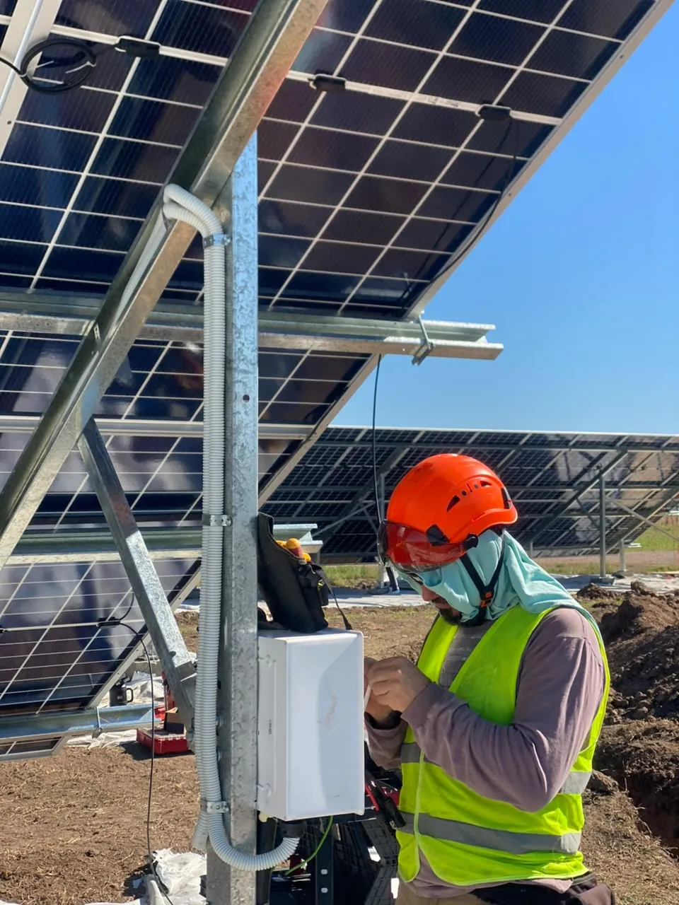 Técnico conectando una caja de strings bajo la estructura de un parque solar