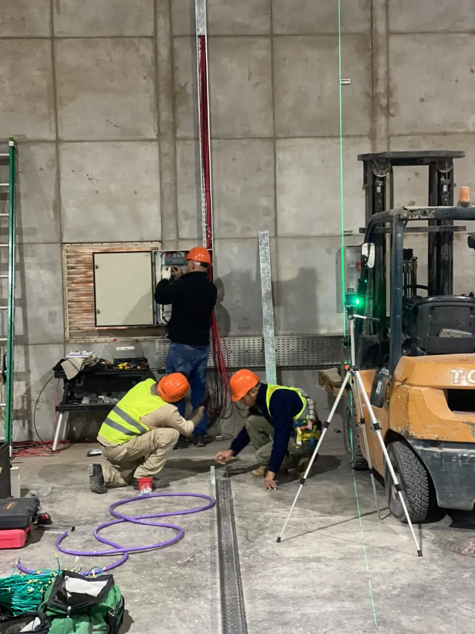 Técnicos instalando un tablero en una nave industrial con láser de nivel